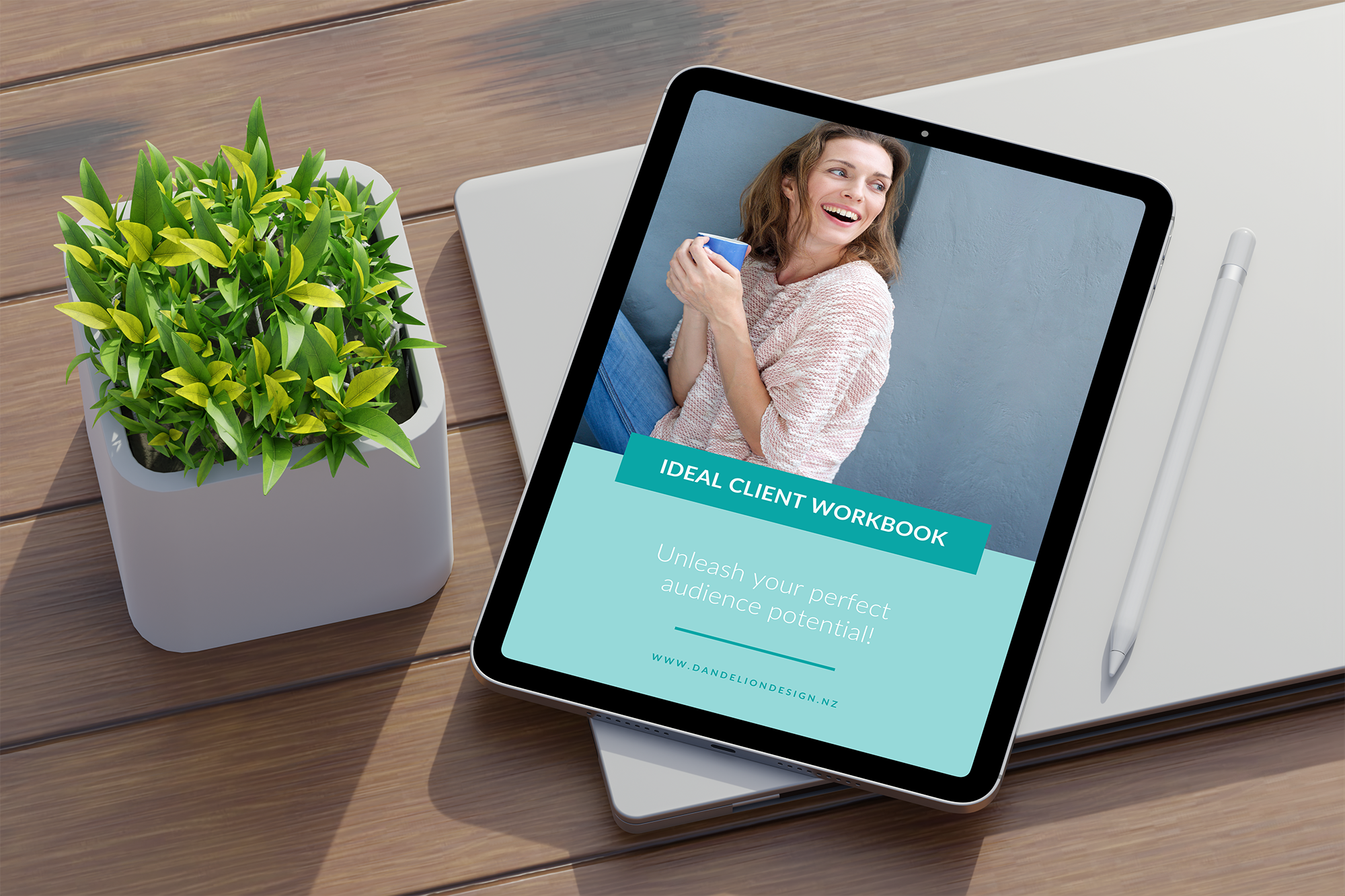 A tablet with a woman's face on it next to a potted plant. The tablet shows a document cover designed by a graphic designer from New Zealand.